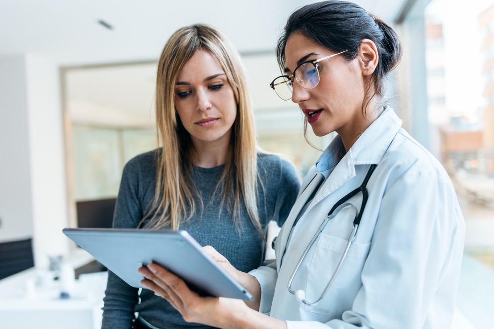 Shot Of Beautiful Female Doctor Talking While Explaining Medical Treatment to Another Lady Shot Of Beautiful Female Doctor Talking While Explaining Medical Treatment to Another Lady